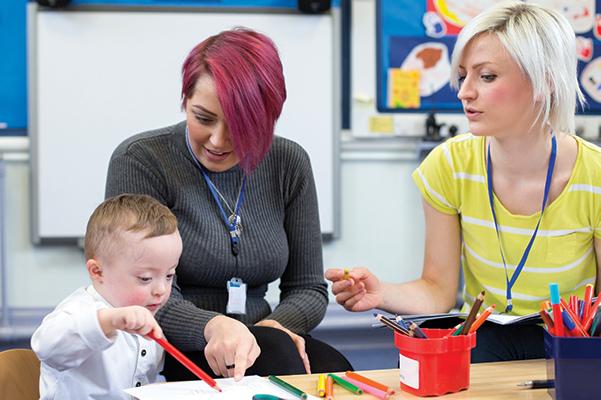 Two women playing with a disabled child
