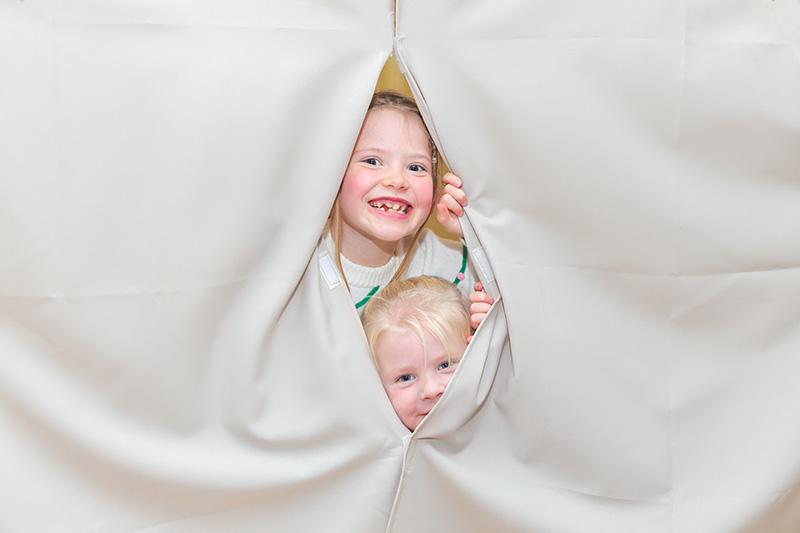 Two children behind a curtain
