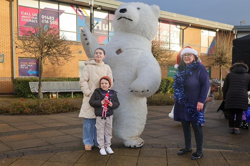 Three people posing with a polar bear